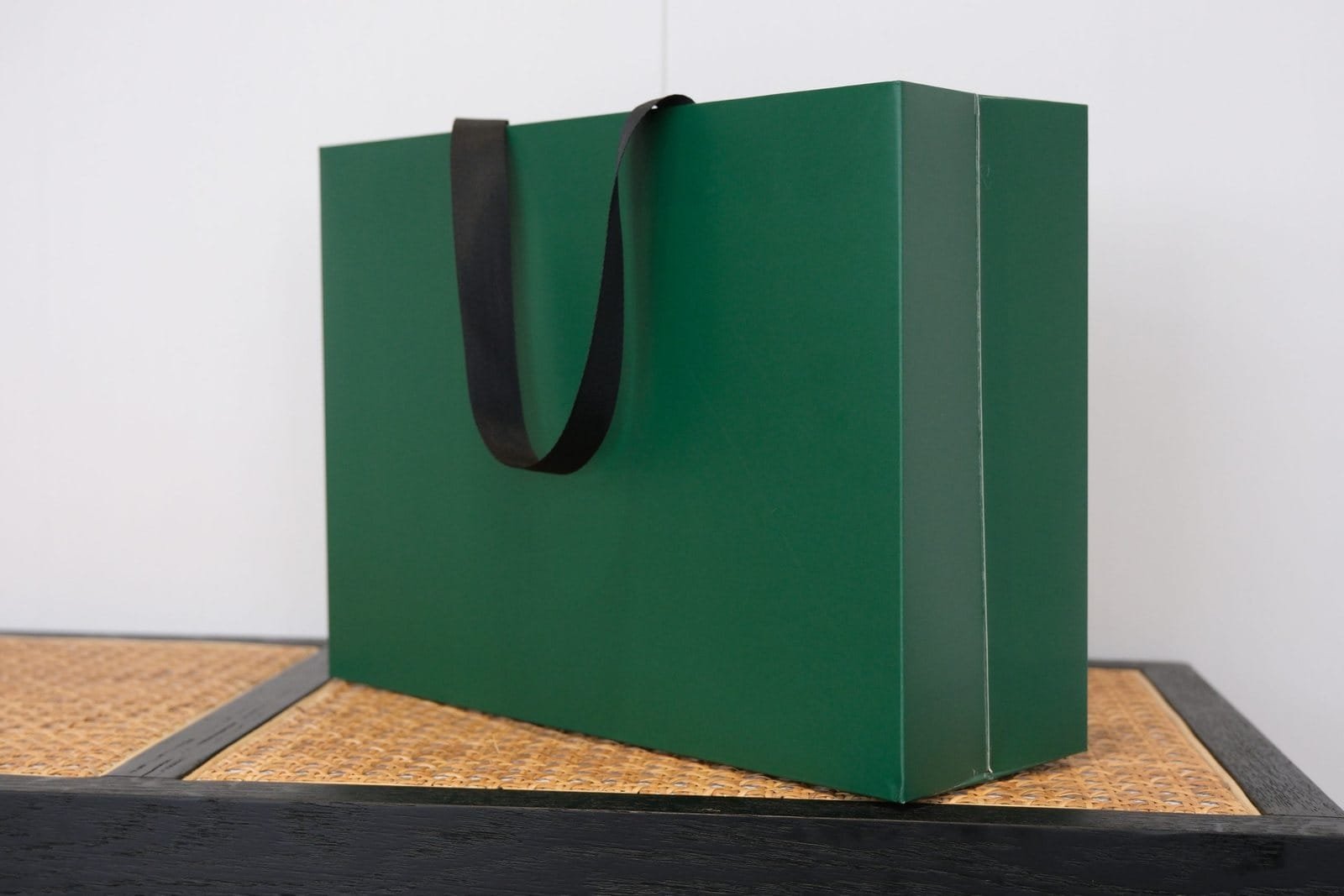 Dark green seamless luxury paper bag sample with black flat ribbon handles