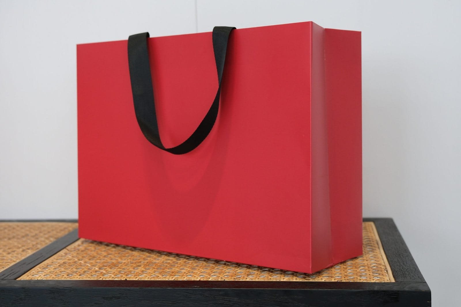 Red seamless luxury paper bag sample with black flat ribbon handles