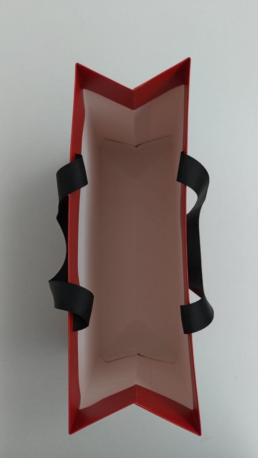 Top view of a paper bag sample showing how the flat ribbon handle is anchored inside the mouth