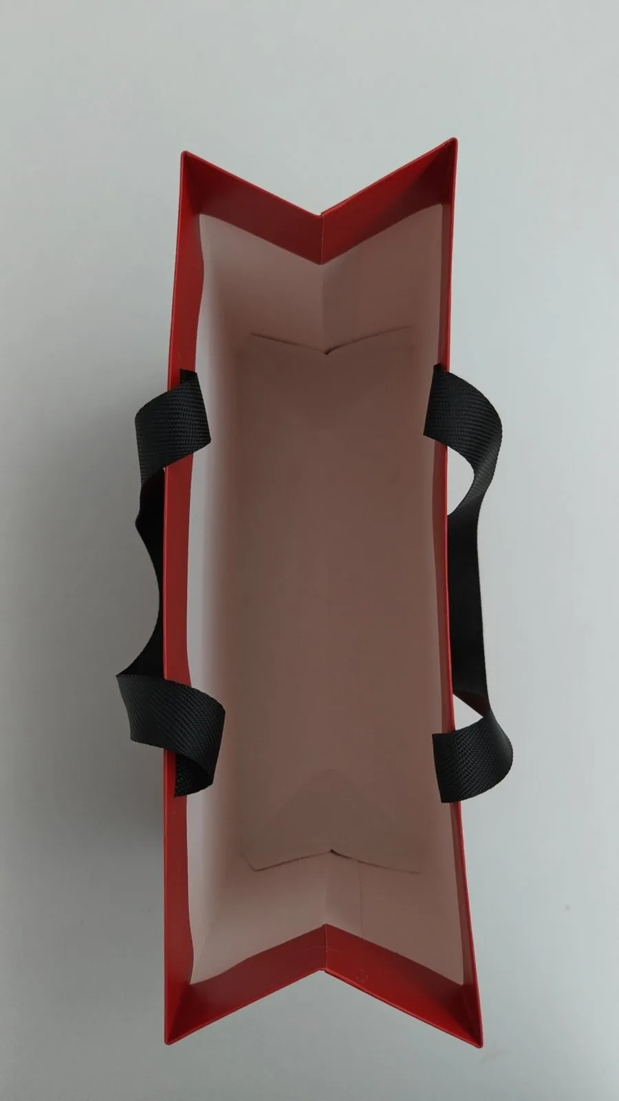 Top view of a paper bag sample showing how the flat ribbon handle is anchored inside the mouth